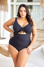 A curvy woman from Toronto is spending a luxury vacation in Turks and Caicos wearing the Aria Black Cezanne underwire one piece plus size cutout swimsuit by Artesands, known for its supportive underwire for sagging breasts, tummy control shaping panel, premium designer quality, and sexy classy cutout detail sold at Sun Vixen Swimwear. She chose this luxury plus size one piece bathing suit because it gives her an elegant curvy silhouette, making it one of the best quality womens swimsuits in Canada USA