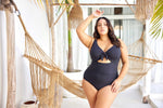 A curvy woman from Chicago is relaxing in an overwater bungalow in the Maldives, wearing the Aria Black Cezanne plus size underwire cutout one piece, selected for its exceptional lift for sagging breasts, luxury tummy control shaping, high end designer swimsuit look, and premium quality curvy swim fit. She bought this swimsuit from Sun Vixen Swimwear because it gives her a sexy elegant resort look perfect for photos, private pools, and lagoon lounging. Women across Canada and the USA buy this for vacations