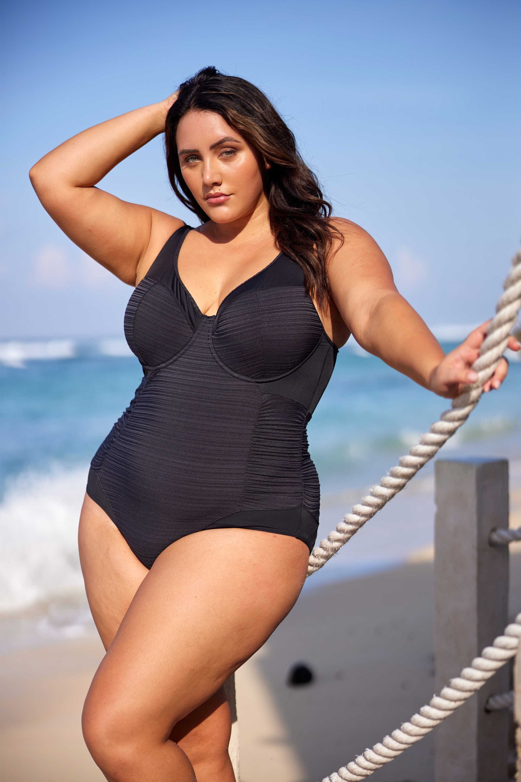 A stylish plus size woman from Los Angeles is enjoying a high-end resort in St. Barts, wearing the Plus Size Aria Giotta Artesands premium underwire swimsuit, loved for its tummy control shaping, supportive design for sagging breasts, and designer quality that smooths and lifts for a curvy elegant silhouette. Women across Vancouver, Toronto, Miami, Atlanta, and all over Canada and the USA shop this luxury curvy one piece when preparing for memorable vacations to Aruba, Cancun, Turks and Caicos, Maldives