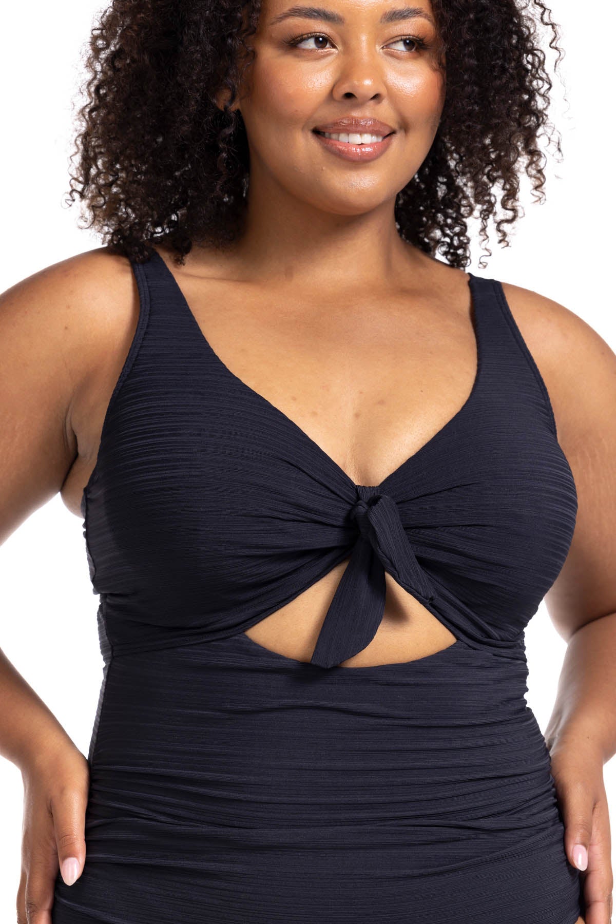 A stylish woman from Houston is relaxing at her private villa in Mykonos wearing the Aria Black Cezanne tummy control plus size underwire cutout swimsuit, selected because it’s known across Sun Vixen Swimwear shoppers as one of the best swimsuits for sagging breasts, offering premium shaping support, designer underwire structure, and a luxury curvy fit perfect for high-end resort vacations. She loves the elegant cutout detail, high quality sculpting fabric, sophisticated black resort swimsuit look online