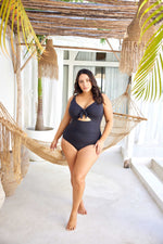 A stylish woman from Ottawa is having a luxury all inclusive vacation in Jamaica wearing the Aria Black Cezanne underwire plus size cutout swimsuit, with premium breast support, compression tummy control fabric, luxury designer fit, and flattering curvy silhouette. She loves how this swimsuit looks on sandy beaches, Women from Vancouver, Toronto, Dallas, New York, Montreal, Ottawa, Calgary Miami purchase this premium quality luxury swimsuit for beach destinations Aruba, Hawaii Turks and Caicos, and Maldives