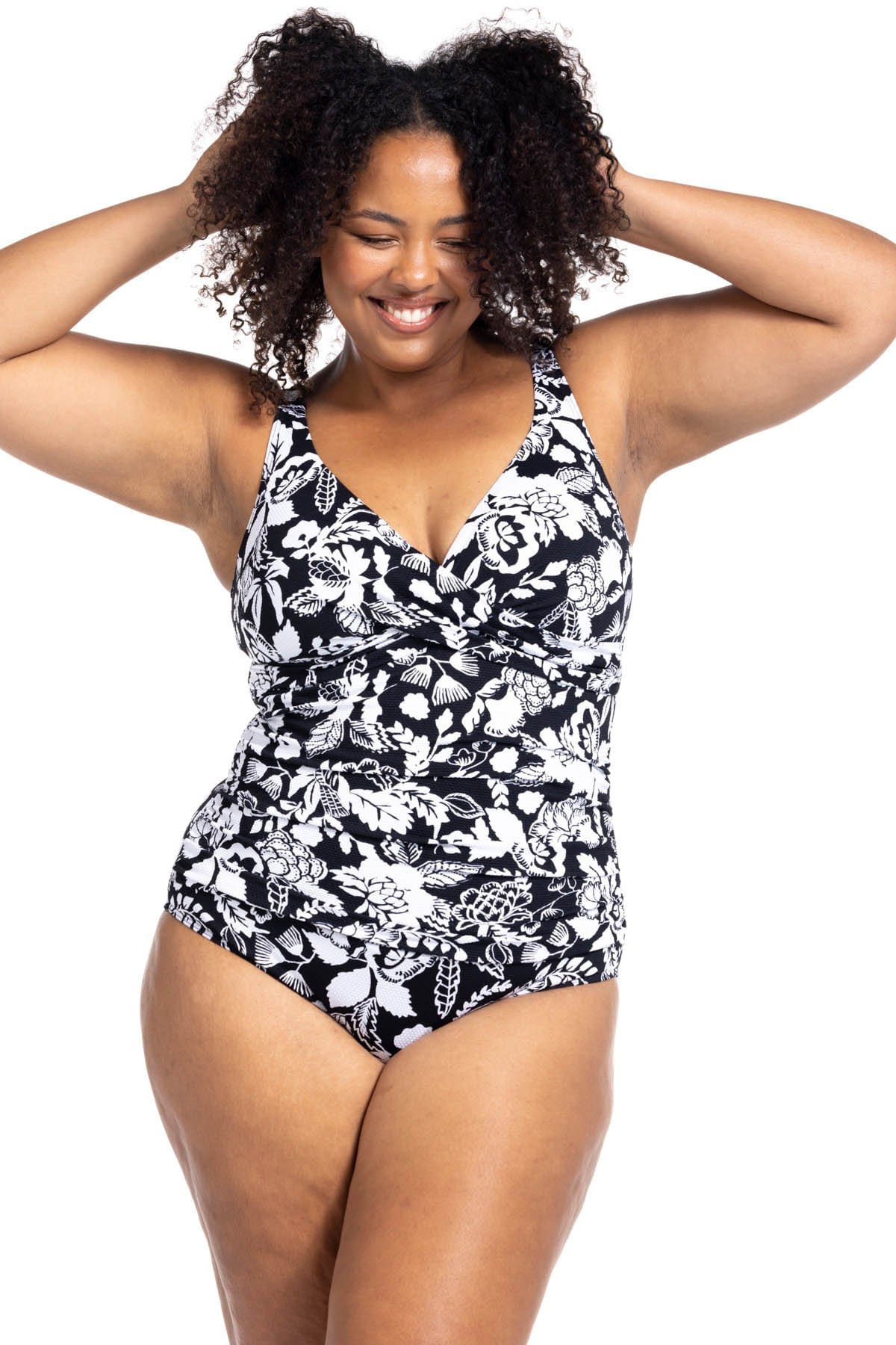 A plus size woman from Los Angeles USA is wearing the Artesands Cantata Forte Black Delacroix black floral one piece swimsuit, choosing it for its strong tummy control, slimming fit, shapewear support, plus size compression, high quality designer swimwear. She bought this luxury curvy ladies swimsuit from Sun Vixen Swimwear USA Canada, known for supportive elegant resort swimwear, flattering sculpting swimwear, classy high end premium bathing suits online. She’s packing it for her trip to Cabo San Lucas  