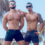 A hot guy wears stylish short swim trunks from Sun Vixen Swimwear on his resort vacation, showcasing sleek black swim trunks that complement his physique. These fitted swim trunks, featuring a slim fit design and 4 inch inseam, are among the best men's swim trunks look. This mens designer swimwear store sell mens short swim trunks and euro style swim shorts. The collection includes slim fit swim trunks, tight swim shorts, and mens 5 inch swim trunks with a mesh liner, sexy swim trunks, cool mens swimwear