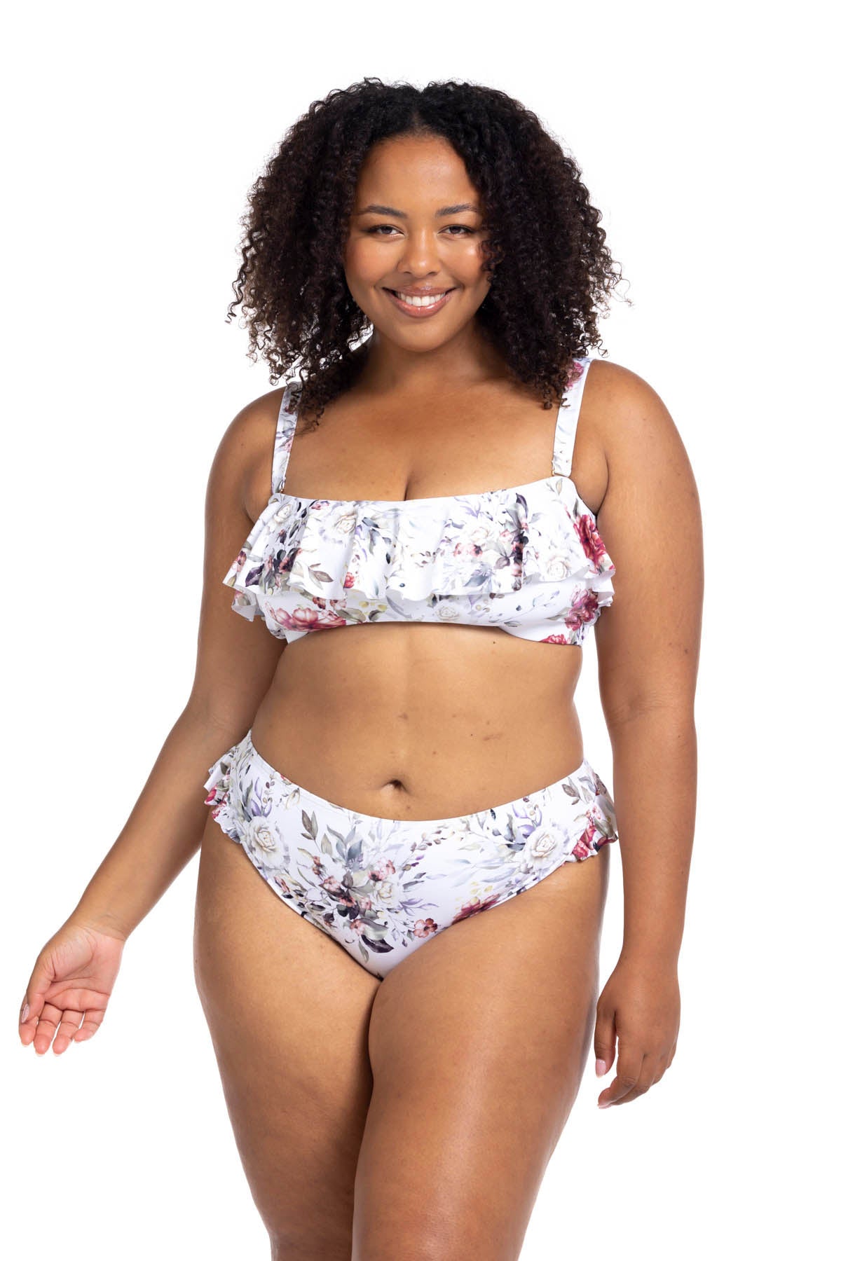 A curvy traveler from Phoenix Arizona is lounging in her Clementine White Vermeer flounce bikini by Artesands, a pretty floral plus size two piece bikini with ruffle details and sculpting high waist compression bikini bottoms. She shops at Sun Vixen Swimwear USA for slimming supportive shapewear swimsuits and the best tummy control bikinis for moms who want classy but sexy plus size swimsuits. The floral print gives her fresh feminine beach look. The supportive top makes her feel secure and lifted 