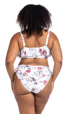 A curvy woman from Houston Texas is wearing the Clementine White Vermeer plus size flounce bikini on her resort vacation, frilly floral bikini top, sculpting high waist bikini bottoms, with compression tummy control fit. She shops at Sun Vixen Swimwear USA for the best plus size swimsuits and flattering luxury supportive bikinis for moms who want something sexy yet classy. The ruffle details give her a elegant but elevated look. The compression bikini bottoms slims her waistline and keeps her comfortable 