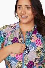 A woman from Ottawa Canada arrives in Hawaii for her beach retreat wearing Artesands Salmagundi Seurat SPF Sun Suit, colorful zip front half sleeve one piece swimsuit with shaping tummy control, sun protection, and flattering fit for her curves. She bought it from Sun Vixen Swimwear USA Canada, her favourite boutique for plus size luxury swimwear, compression tummy control bathing suits, and resort designer swimwear. Customers from Montreal Dallas shop for sexy slimming swimsuits, high quality bathing suits