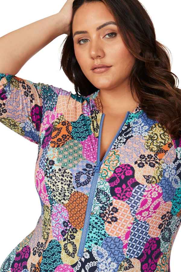 A stylish curvy woman from San Diego USA is in Cabo San Lucas wearing Artesands Salmagundi Seurat Sun Suit the colorful patch print SPF one piece swimsuit with zippered front and half sleeve swimsuit design. She purchased it from Sun Vixen Swimwear, her trusted boutique for supportive curvy swimwear, luxury plus size bathing suits, and designer tummy control swimsuits that flatter her shape. The sculpting compression fabric slims tones her belly, the colorful design gives her a rich resort beachwear look 