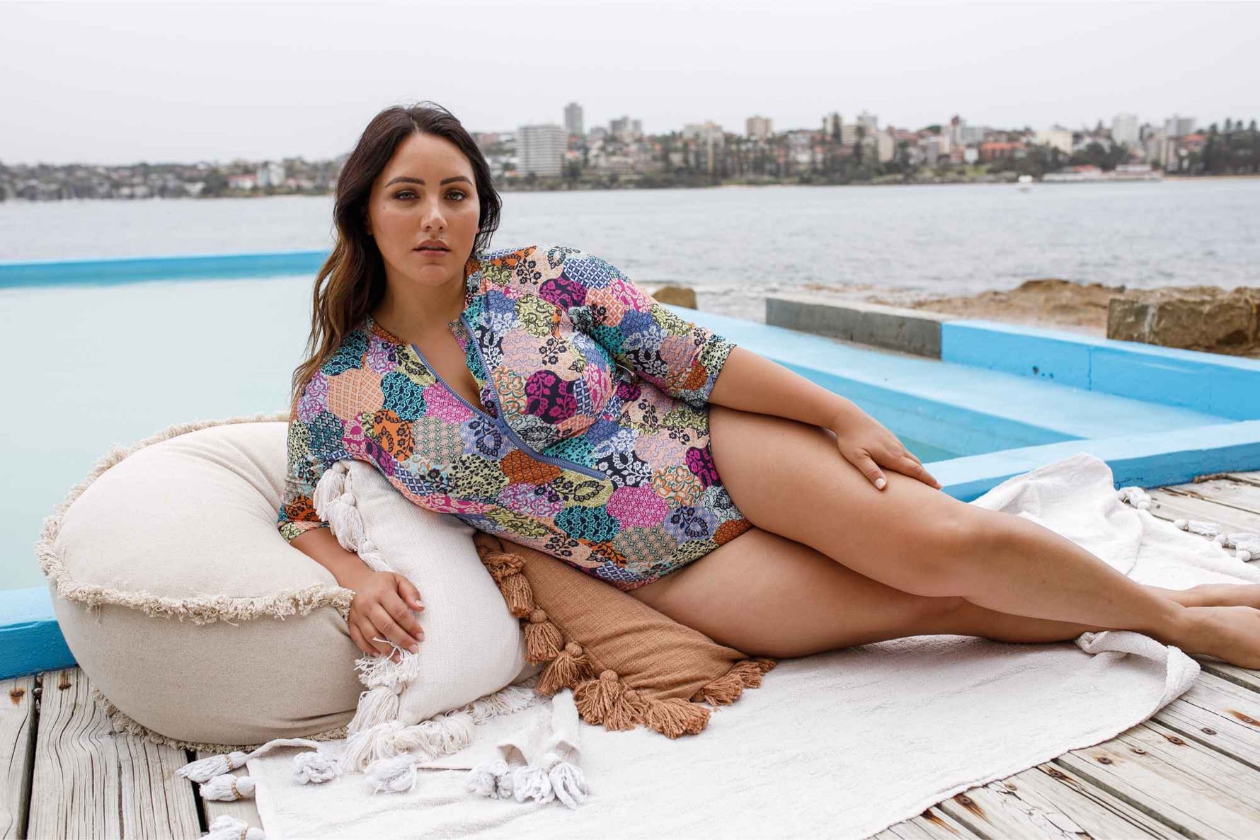 A curvy plus size woman from Miami USA is wearing the Salmagundi Seurat Sun Suit by Artesands, a colorful patch print SPF half sleeve one piece with zip front closure that makes it, stylish, slimming and ultra supportive for her beach holiday. She bought this designer plus size swimwear from Sun Vixen Swimwear USA Canada, the best online boutique for sexy slimming swimsuits, tummy control shaping swimwear, and high quality curvy swimsuit. She’s shopping for resort swimwear for her luxury vacation in Cancun