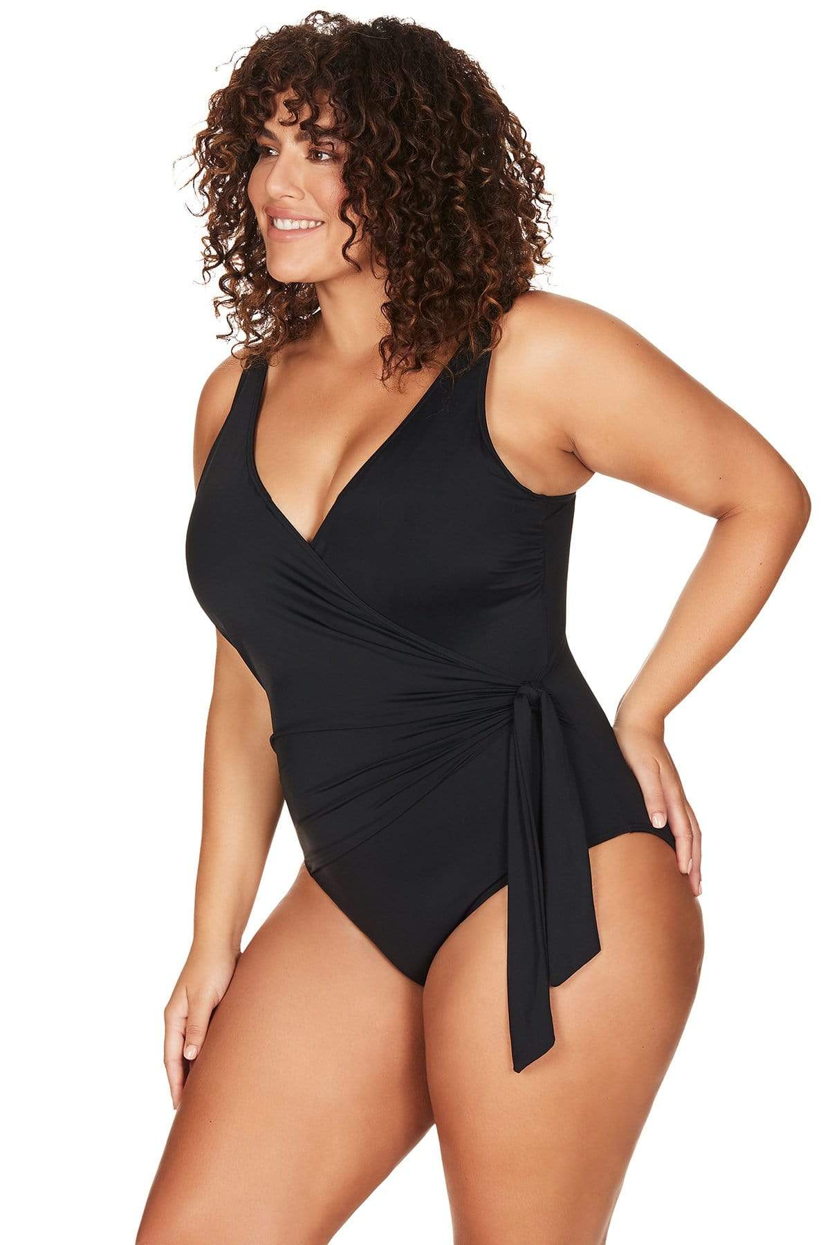 A plus size traveler from London is lounging at a resort spa in her Tummy Control Plus Size Swimsuit Black Artesands Hayes design, loving the wrap front shaping swimsuit design that smooths her tummy and defines her curves. She chooses luxury womens swimwear with supportive underwire and high quality slimming fabric that keeps her feeling upscale timeless and sophisticated. This classy black swimsuit makes her feel slimmed oned and comfortable for her elegant European getaway. Shop good quality ladies swim