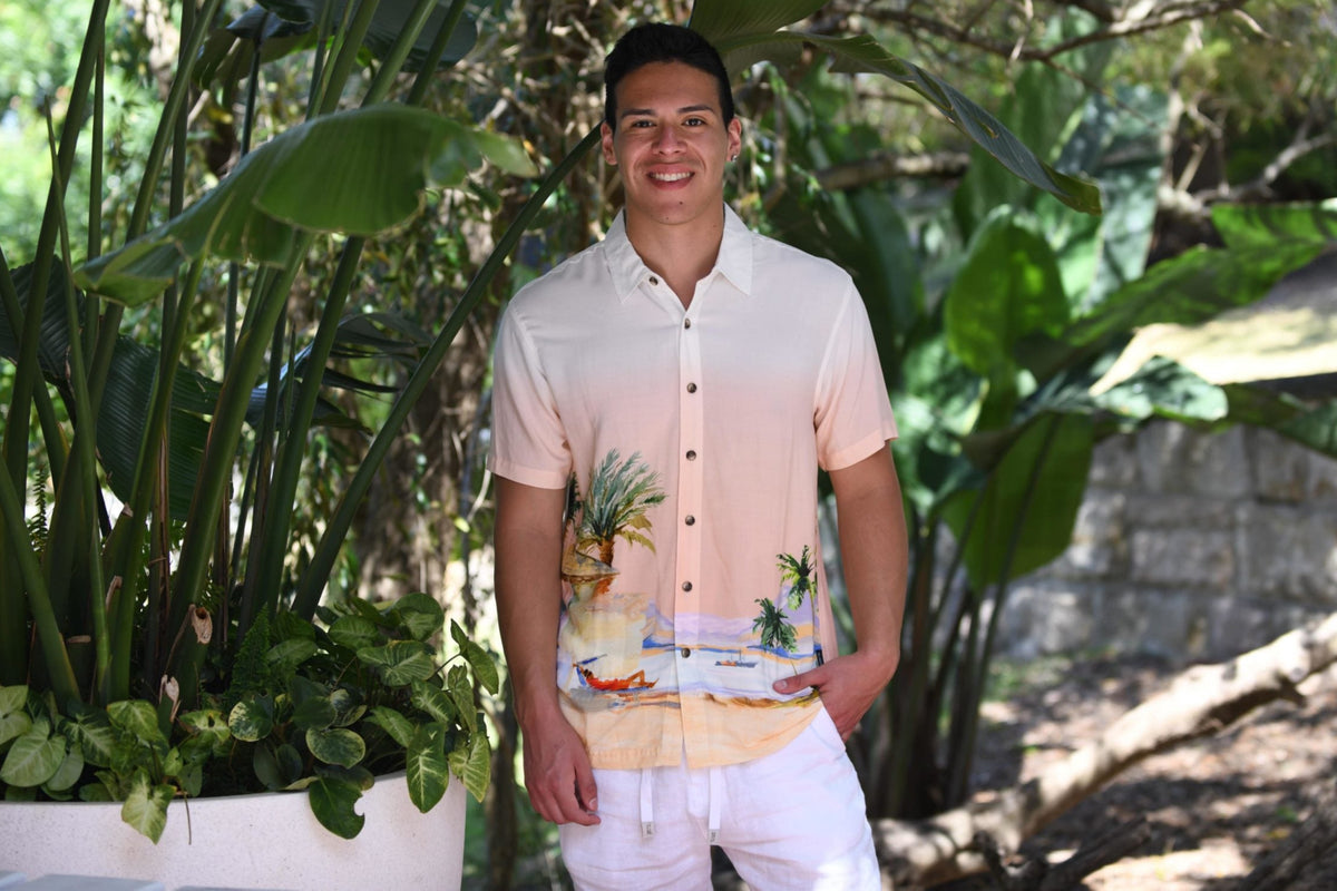 A stylish man wears a designer Hawaiian beach shirt from Sun Vixen Swimwear on a tropical vacation. This mens designer swimwear store offers the best luxury beach shirts, featuring floral beach shirts, designer mens beachwear, and premium resort shirts, perfect for a smart resort  beach look. This mens designer swimwear store features the best luxury beach shirts, cool beach shirts, sustainable mens beachwear, and tropical shirts, stylish resort shirts, and stylish resort shirts, high end designer beachw