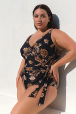 A curvy woman from Los Angeles USA is wearing the black one piece swimsuit tummy control Plus Size Chantique Hayes D/DD Cup Underwire One Piece Swimsuit she ordered from Sun Vixen Swimwear for her luxury escape to Maui. The black floral print and supportive underwire shape her waist with flattering compression that feels high end and elegant. She loves investing in designer luxury swimwear, that offer tummy control and a sexy, classy look for premium resort vacations. this is best quality slimming swimsuit
