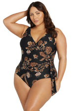A confident woman from Chicago USA slips into the Plus Size Chantique Hayes D/DD Cup black floral tummy control one piece swimsuit for her beach holiday in Turks and Caicos, loving how the underwire and sculpting panel slims her shape. She likes shopping for high quality designer swimsuits that feel sophisticated for luxury travel. Slimming compression flattering bathing suit make her look sexy and polished for upscale pool cabanas, private villa stays. Shop now fashion womens swimwear online USA Canada