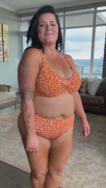 A plus size woman from Toronto is relaxing in her boutique hotel wearing the Copper Monet cheetah print tummy control bikini set from Artesands that she bought online from sun vixen swimwear. The soft cup underwire top gives her natural lift while the high waist bikini bottoms smooth her midsection for a flattering curvy silhouette. She loves sophisticated plus size designer swimwear that gives confidence for beach trips in Cancun Mexico. Shop plus size womens swimwear USA Canada online boutique website 