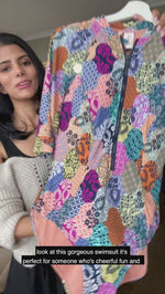 A stylish woman from Toronto Canada wears her new Artesands Salmagundi Seurat Sun Suit colorful half sleeves zippered one piece swimsuit with SPF, Artesands tummy control swimwear. She ordered it from Sun Vixen Swimwear, known for carrying the best plus size swimsuits, supportive tummy control one piece bathing suits, and luxury curvy swimwear for women who want elegant resort swimsuits. She’s packing this flattering zip front swimsuit for tropical trip to Maui that lifts her bust, and slims her belly pooch