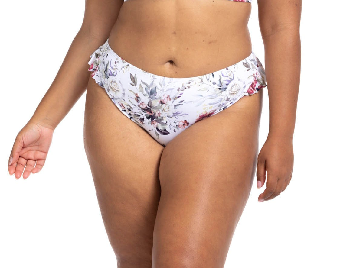 A plus size woman from Quebec City Canada is enjoying her spa retreat in the Artesands Clementine White Vermeer frilly ruffle bikini, impressed by the floral aesthetic and high waist shapewear-like compression that flatters her curves beautifully. She ordered it from Sun Vixen Swimwear, her favourite boutique for classy plus size swimwear, sexy tummy control bikinis, and the most flattering curvy swimsuits online. She loves how elegant the floral print swimsuit, supportive bikini looks on relaxing getaway