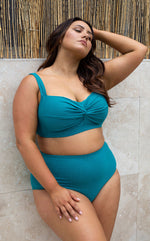 A curvy woman from Miami Florida is wearing the Rhapsody Teal Botticelli plus size underwire bikini top with high waist tummy control bikini bottoms by Artesands, choosing this designer womens swimwear for its sexy slimming fit and sophisticated support. She bought it from Sun Vixen Swimwear USA because she loves classy womens swimwear that flatters bigger women on beach vacations. She only shops at trusted luxury boutiques that offer the most flattering swimsuits for plus size curvy ladies swimwear Canada