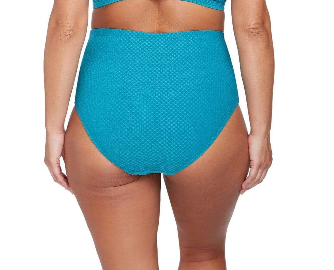 A curvy woman from Seattle Washington is enjoying her beach resort morning in the Rhapsody Teal Botticelli plus size underwire bikini top and high waist tummy control bikini bottoms from Artesands, with its sculpting and sophisticated silhouette. She found it at Sun Vixen Swimwear USA, her go to boutique for sexy slimming swimsuits, classy womens swimwear, and the most flattering swimsuits for plus size women who love stylish, good quality pieces. She loves discovering the best places to buy high end swim
