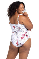 A stylish woman from San Diego is relaxing at a beachfront villa in Bora Bora wearing the Clementine White Hayes tummy control underwire one piece plus size wrap swimsuit by Artesands, a favourite among women wanting luxury supportive swimwear, lift for sagging breasts, high quality shaping design, designer resort swimwear, and premium curvy beachwear. She purchased it from Sun Vixen Swimwear because it delivers a classy sophisticated resort swimsuits for upscale tropical vacations. Women shop  USA Canada