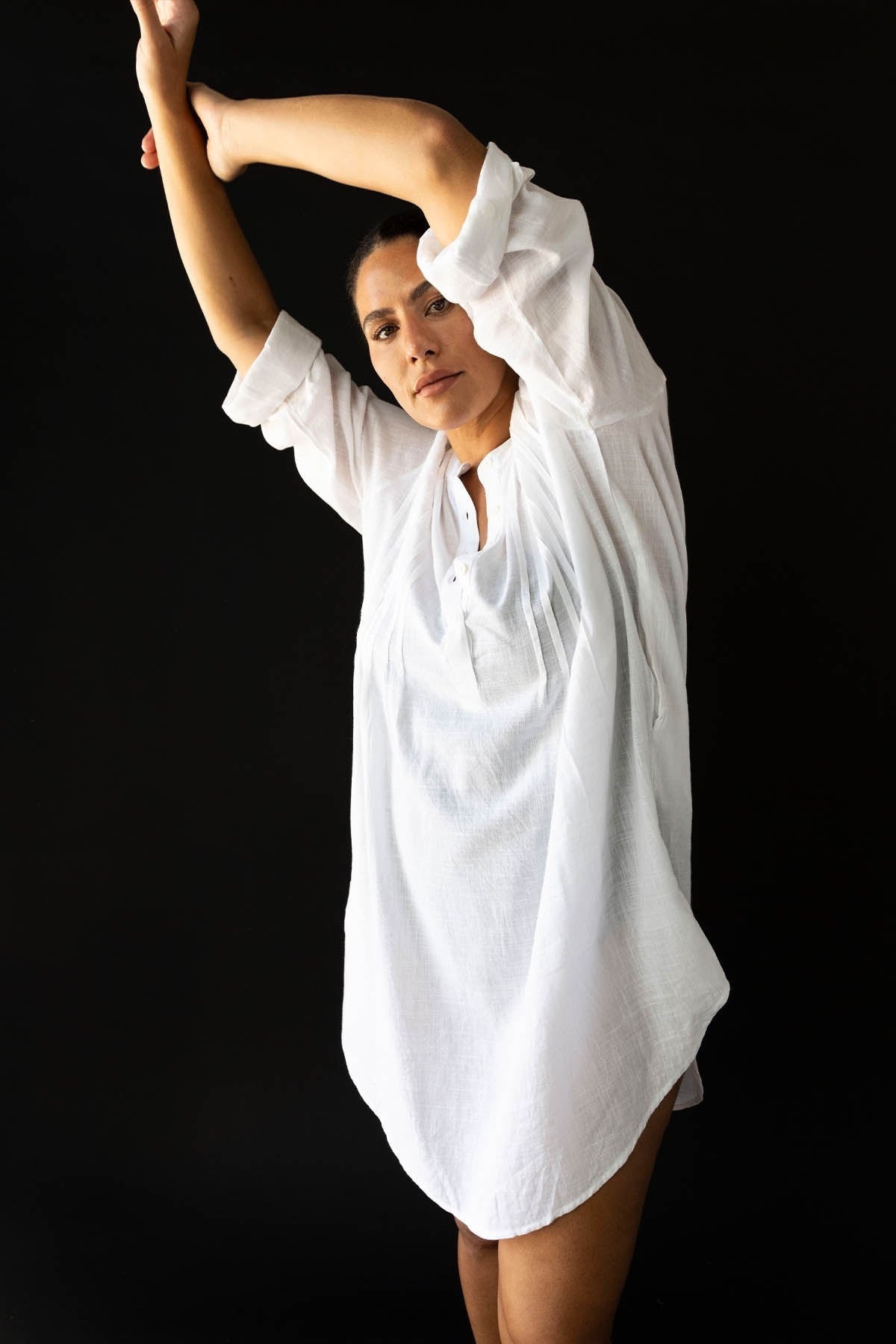 A woman from Seattle is enjoying a romantic getaway in Santorini wearing the Artesands white Gershwin long sleeve over shirt cover up, known across Sun Vixen Swimwear shoppers as a must have for luxury white swimsuit cover ups, designer beachwear shirts, premium long sleeve resort cover ups, sexy white beach outfit looks, and high quality curvy resort swim. She loves this cover up because it gives her a clean, classy, high end look for pool lounges, luxury cruises, private villas, and beachfront resorts 