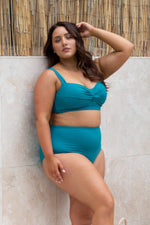 A stylish curvy woman from New York City is wearing the Rhapsody Teal Botticelli plus size underwire bikini top and tummy control bikini bottoms by Artesands during her luxury hotel stay, loving how slimming, supportive, and classy this designer womens swimwear looks on the beach. She ordered it from Sun Vixen Swimwear USA after searching for the best places to buy plus size swimsuits that flatter bigger women and offer a high fashion resort look. She loves sexy curvy swimwear that feels elevated and classy